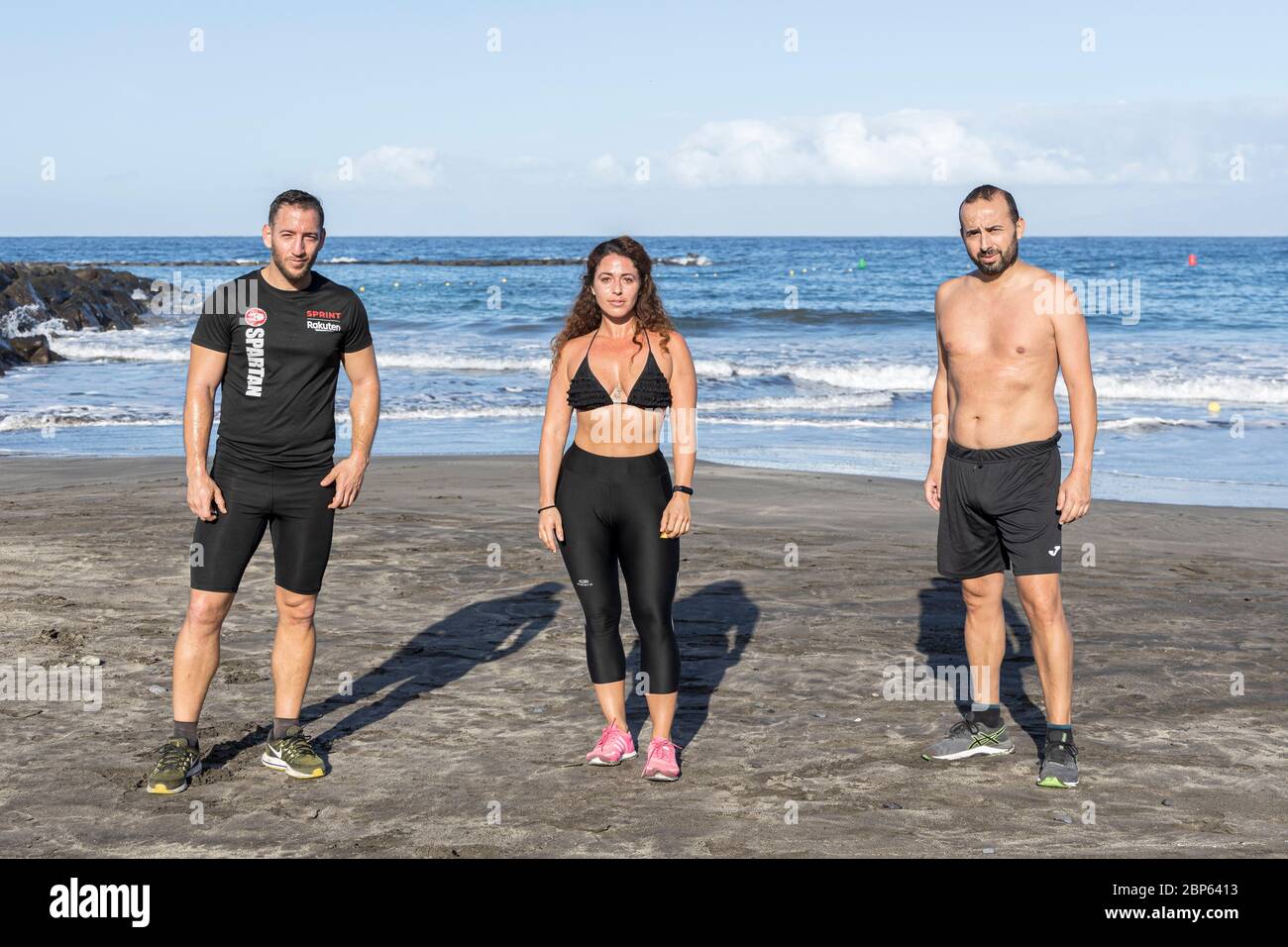 Drei junge Menschen posieren für ein Porträt, während sie während der ersten Phase der Deeskalation des Covid 19 am Strand Playa Fanabe körperliche Distanz wahren, Stockfoto