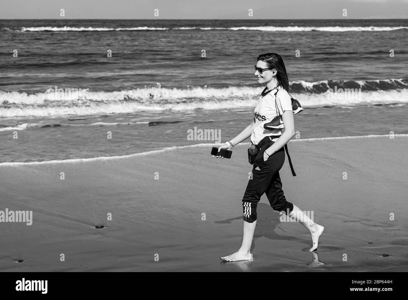 Junge Kanarierin, die am Strand Playa Fanabe in der ersten Phase der Deeskalation des Covid 19 am Strand entlang spazierend, Coronavirus, Notstand, Stockfoto