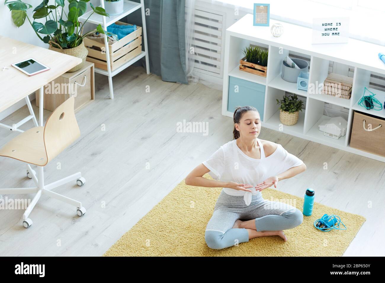 Weitwinkelansicht bei modernen jungen Frau genießen Atemübungen während der Meditation zu Hause, kopieren Raum Stockfoto