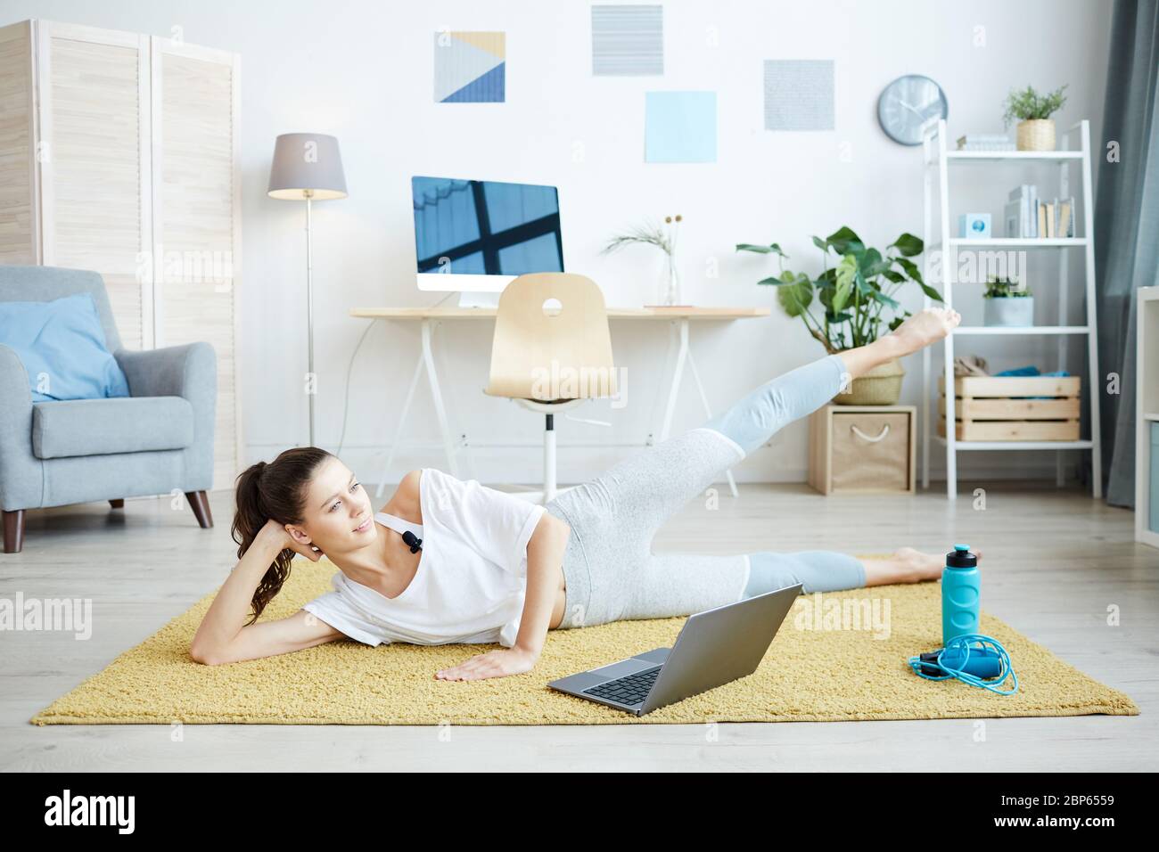 In voller Länge Porträt von lächelnden jungen Frau genießen Home Workout online über Laptop, kopieren Raum Stockfoto