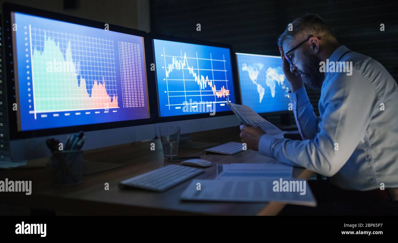 Frustrierter Geschäftsmann mit Computer an der Rezeption, der spät arbeitete. Konzept der Finanzkrise. Stockfoto