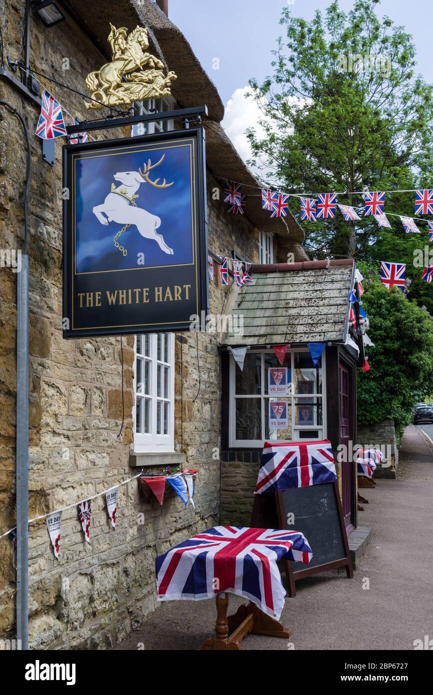 VE Day 75. Jahrestag im Dorf Great Houghton, Northamptonshire, Großbritannien; White Hart Pub mit Union Jacks und Bunting Stockfoto