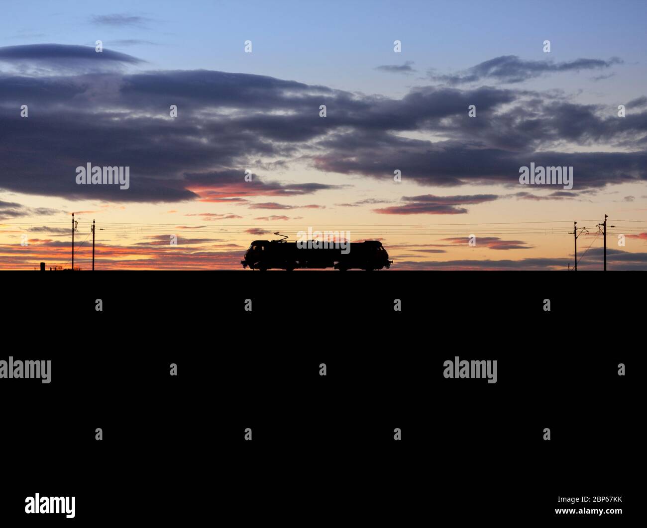 Freightliner 90 elektrische Lokomotive, die bei Sonnenuntergang eine Silhouette auf der Westküsten-Hauptlinie macht, während sie einen leichten Motor läuft Stockfoto