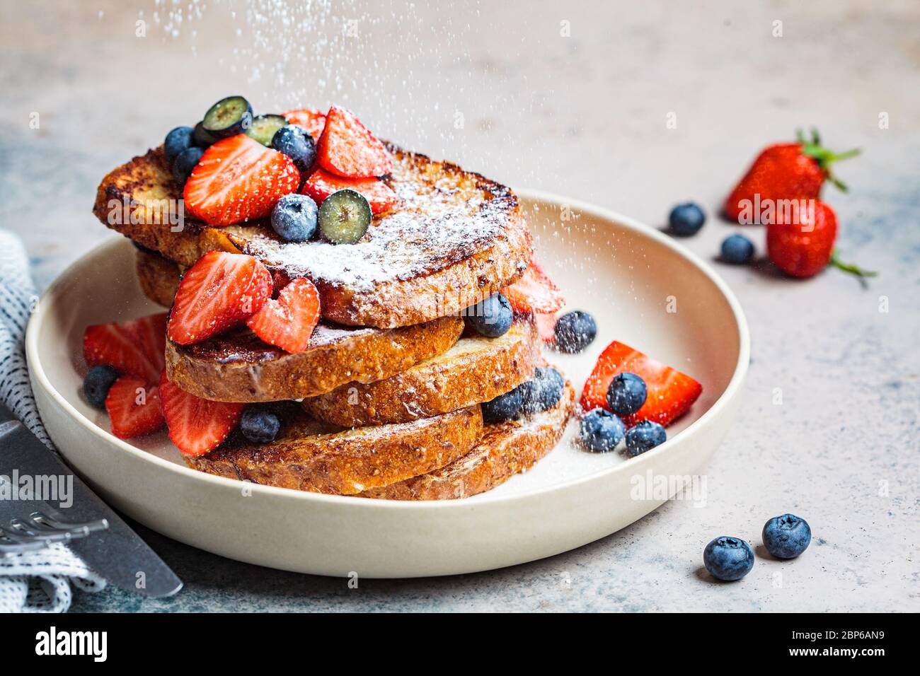 Traditioneller französischer Toast mit Heidelbeeren, Erdbeeren und Puderzucker auf einem weißen Teller. Stockfoto