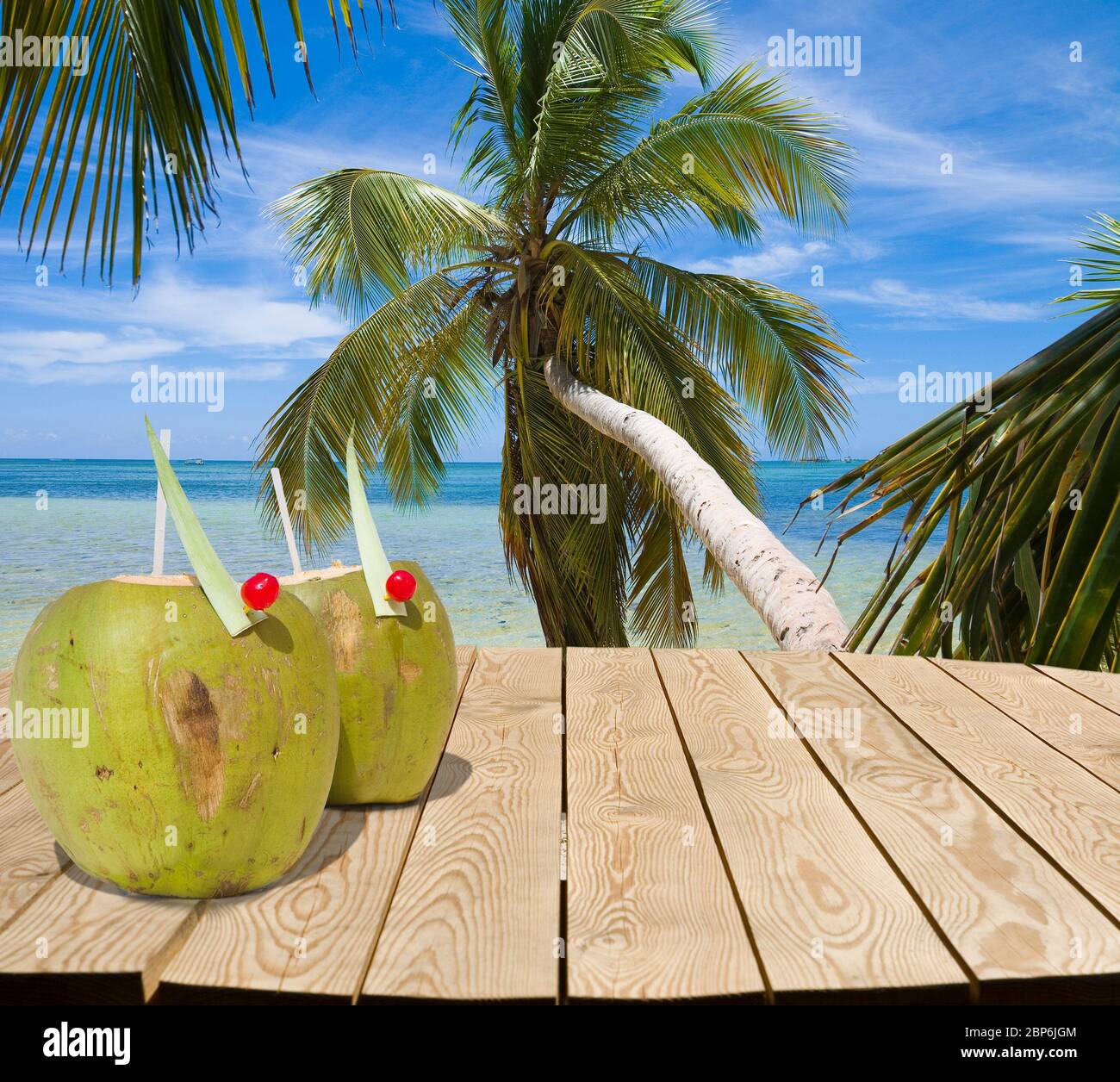 Holztisch mit Kokosnuss-Getränken und Platz für Ihre Produktwerbung. Tropischer Strand im Hintergrund. Sommerurlaub Konzept Stockfoto