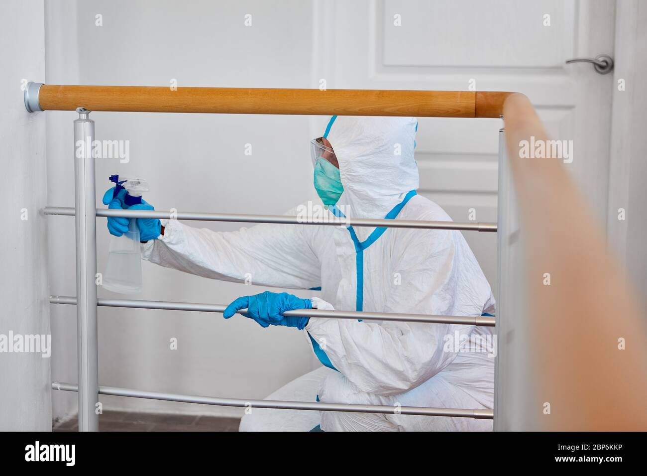 Reiniger in Schutzkleidung desinfiziert Geländer in Kliniken oder Pflegeheimen im Falle einer Coronavirus-Pandemie Stockfoto