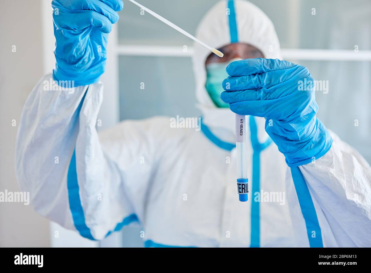Medic in Schutzkleidung verpackt Rachenabstrich aus Speichelprobe für Coronavirus-Test Stockfoto