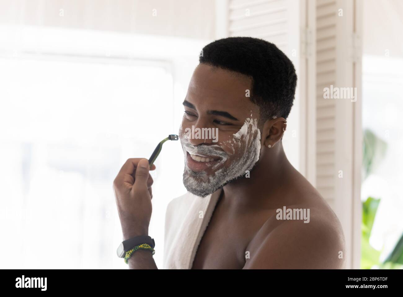 afroamerikanischer Mann schauen im Spiegel Rasieren im Bad Stockfoto
