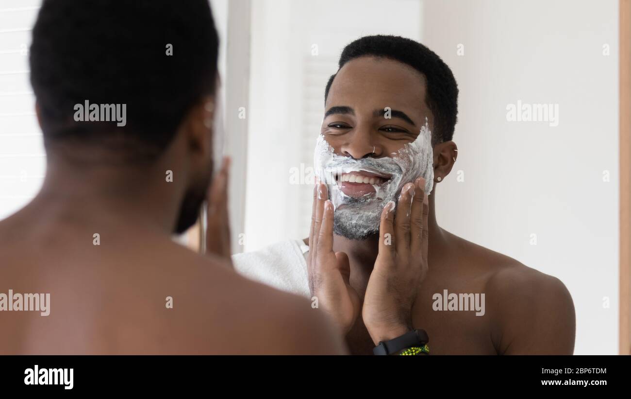 Afroamerikanischer Mann verwenden Schaum Rasierbart im Badezimmer Stockfoto