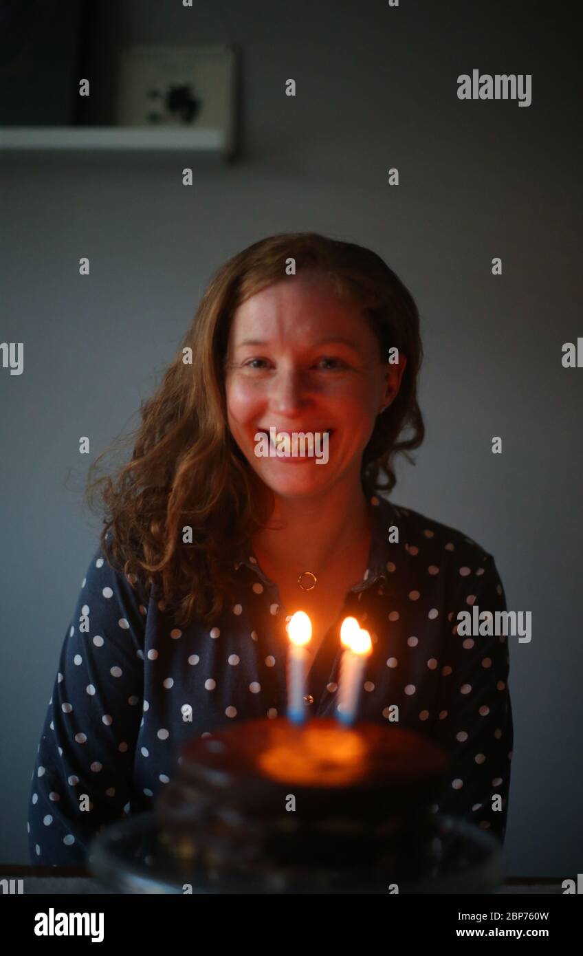 Eine Frau feiert ihren Geburtstag, indem sie die Kerzen auf ihrer Geburtstagstorte in Belfast, Nordirland, ausbläst. Stockfoto