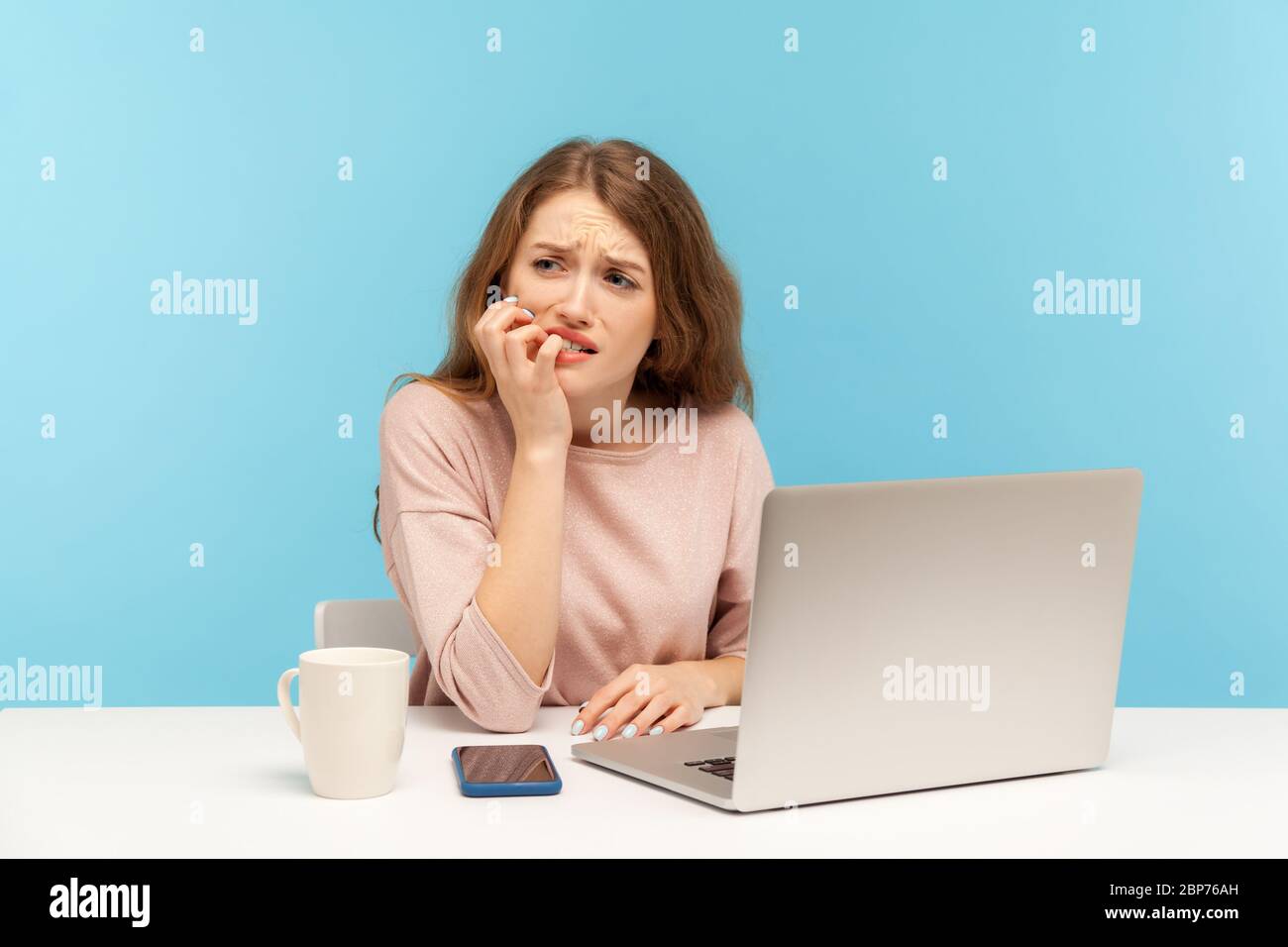 Ängstlich depressive junge Frau Mitarbeiter am Arbeitsplatz mit Laptop und beißende Nägel sitzen, nervös suchen besorgt, Angst vor Frist stressigen Job. ich Stockfoto