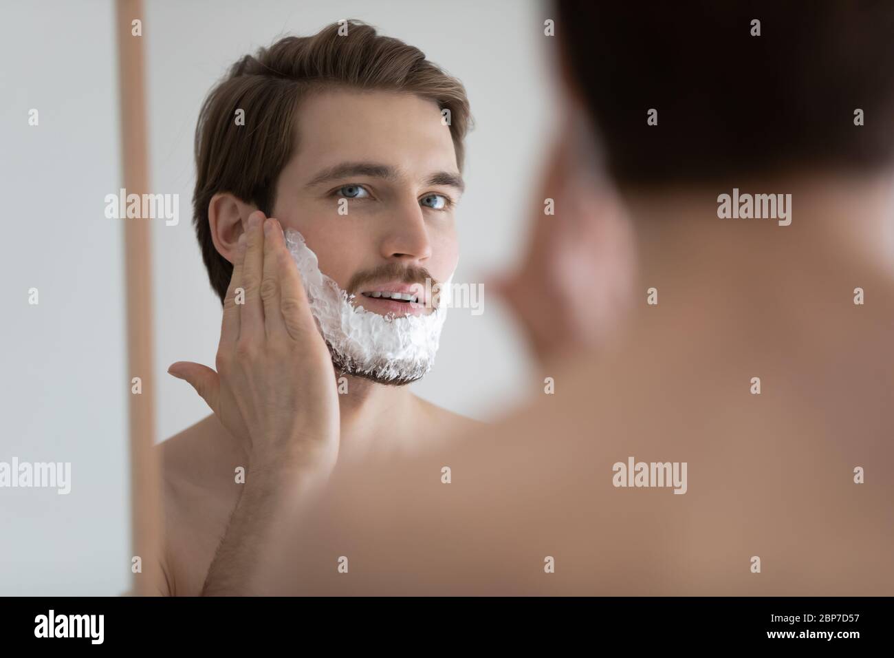 Junger Mann tragen Schaum Rasur im Badezimmer Stockfoto