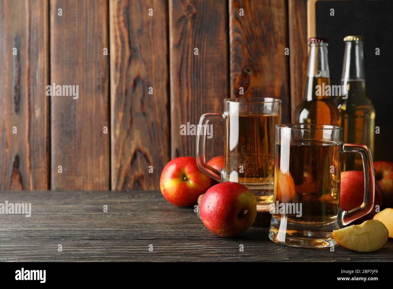 Komposition mit Apfelwein und Äpfeln auf Holzhintergrund Stockfoto
