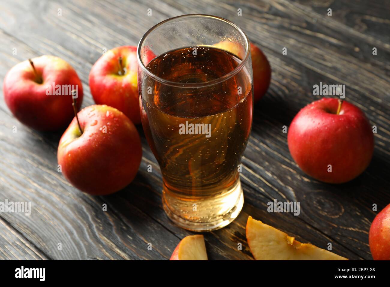Komposition mit Apfelwein und Äpfeln auf Holzhintergrund Stockfoto