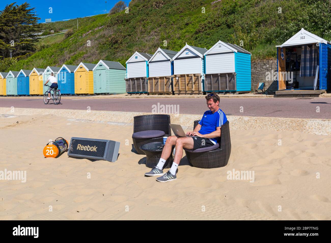 Bournemouth, Dorset, Großbritannien. Mai 2020. Wetter in Großbritannien: Sehr warm und sonnig, die Temperaturen steigen an den Stränden von Bournemouth an, wenn Strandgänger an die Küste fahren, um die Sonne zu genießen. Personal Trainer Gavin arbeitet am Strand während der Coronovaris Covid-19 Einschränkungen. Gavin's Strandhütte (rechts) brannte und wurde am 20. Juli 2020 beim Brand am Bournemouth Beach zerstört. Quelle: Carolyn Jenkins/Alamy Live News Stockfoto