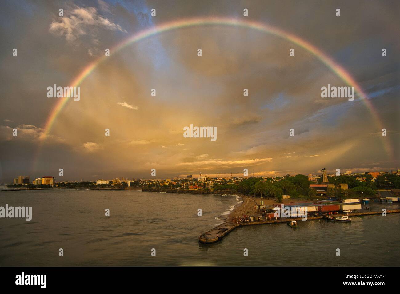 Blick über Santo Domingo auf der Insel der Dominikanischen Republik, der Karibik, Westindien. Ein voller Regenbogen erhellt den stürmischen Himmel und die Wolken Stockfoto