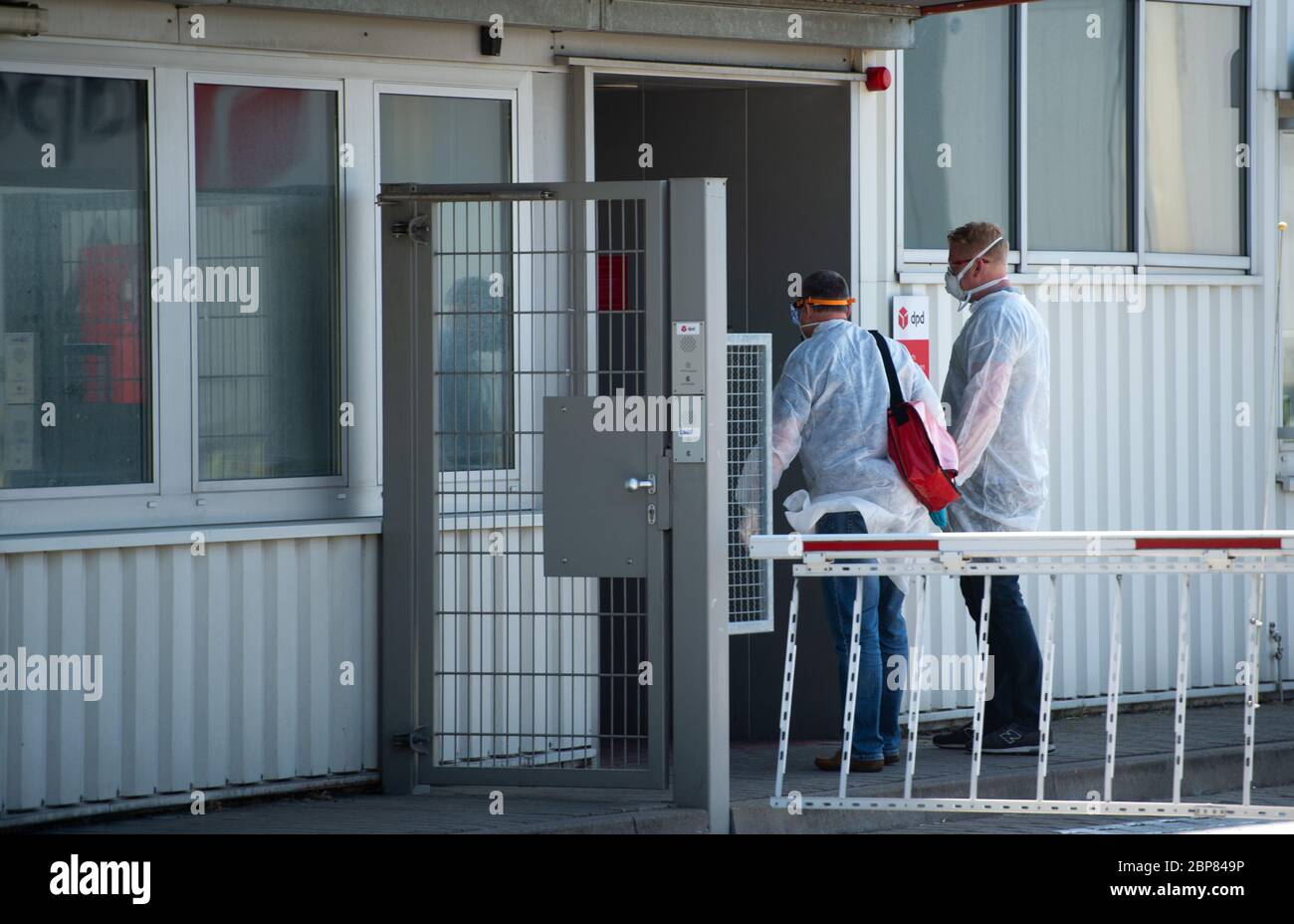 18. Mai 2020, Nordrhein-Westfalen, Hückelhoven-Hilfarth: Zwei Mitarbeiter eines Desinfektionsdienstes betreten das Gebäude des Paketzustellers DPD mit Schutzausrüstung. Das Logistikunternehmen hat seinen Standort in Hückelhoven im Kreis Heinsberg mit 400 Mitarbeitern aufgrund eines Corona-Ausbruchs vorübergehend geschlossen. Foto: Jonas Güttler/dpa Stockfoto