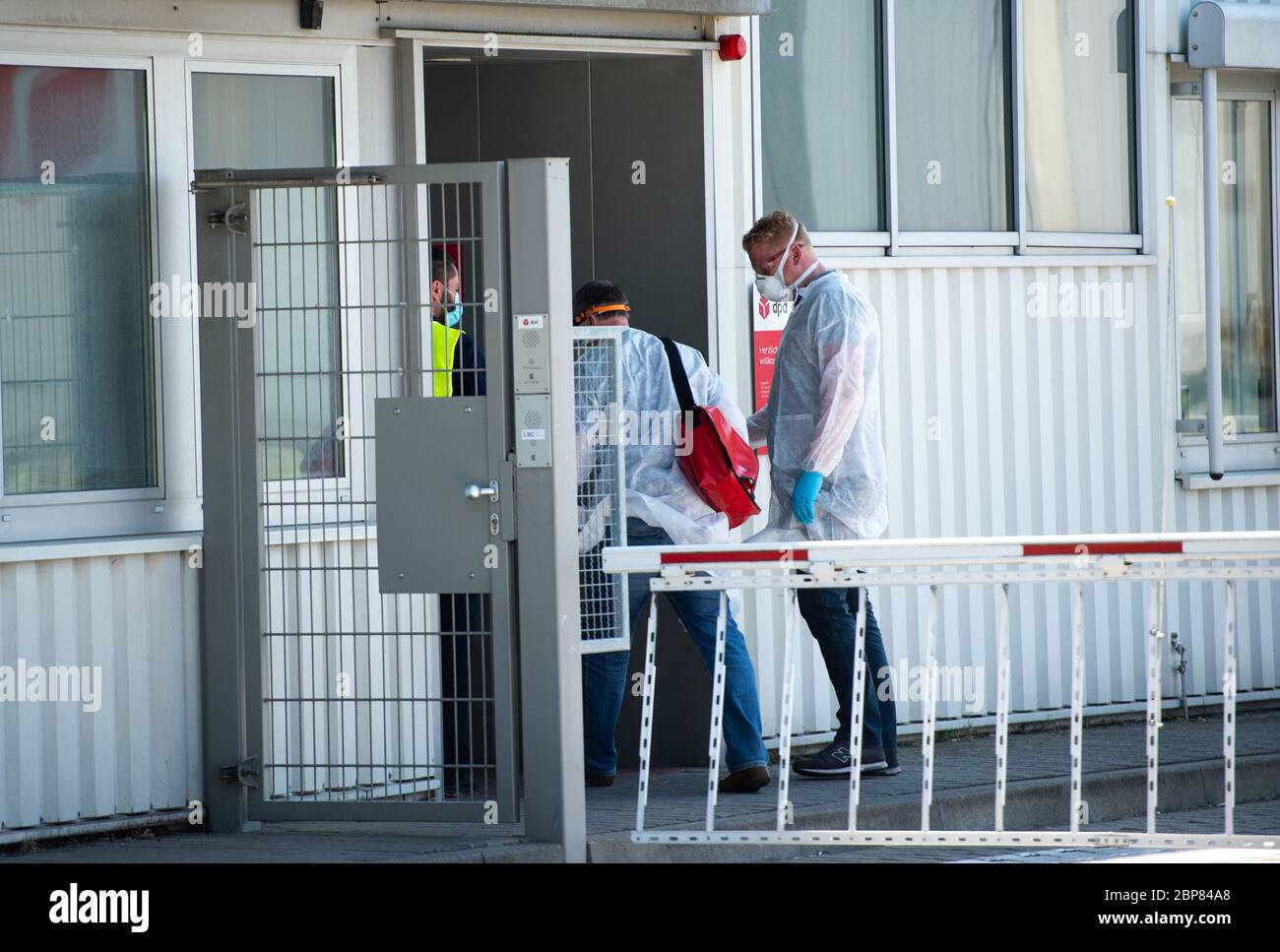 18. Mai 2020, Nordrhein-Westfalen, Hückelhoven-Hilfarth: Zwei Mitarbeiter eines Desinfektionsdienstes betreten das Gebäude des Paketzustellers DPD mit Schutzausrüstung. Das Logistikunternehmen hat seinen Standort in Hückelhoven im Kreis Heinsberg mit 400 Mitarbeitern aufgrund eines Corona-Ausbruchs vorübergehend geschlossen. Foto: Jonas Güttler/dpa Stockfoto