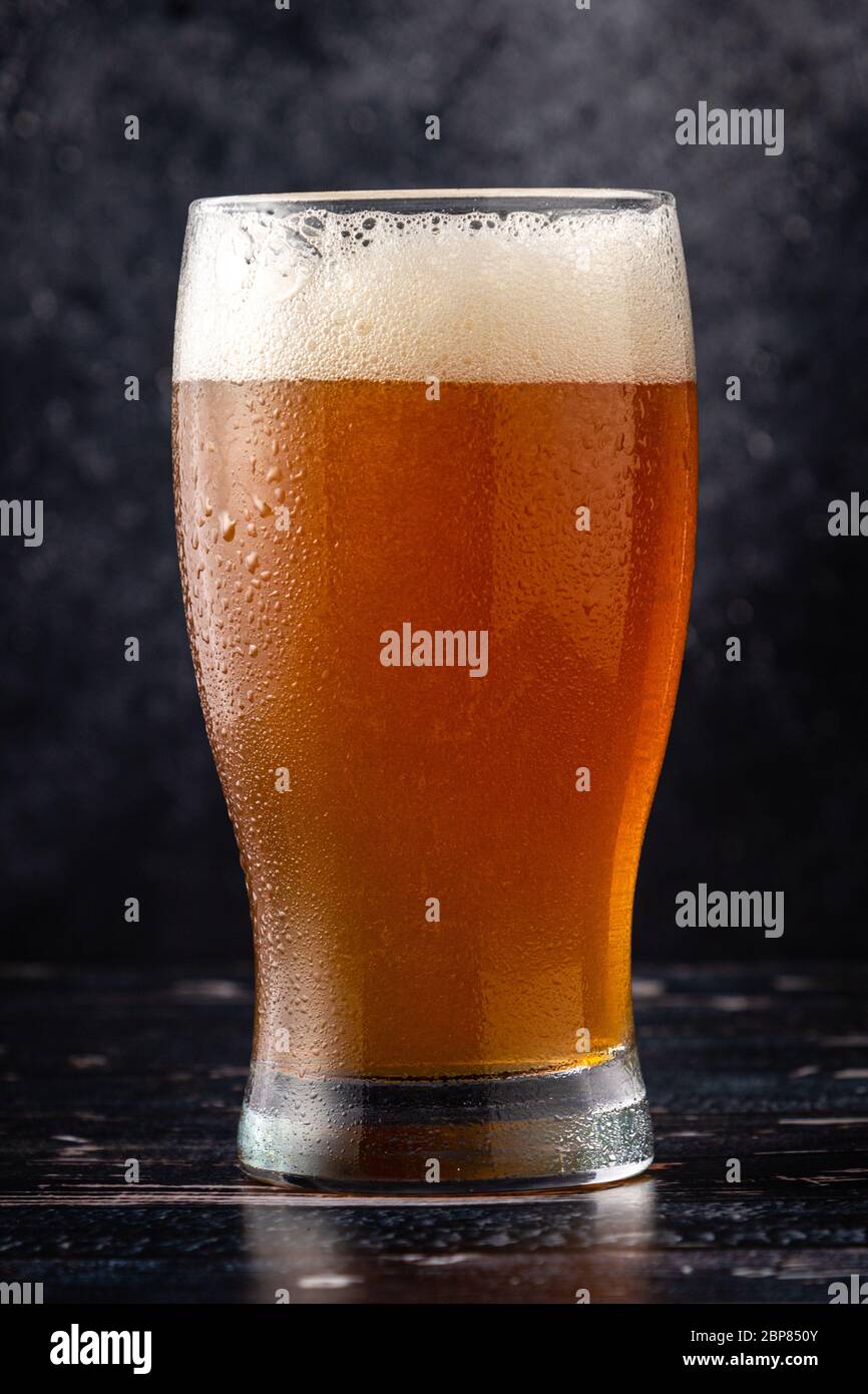 Glas Bier auf dunklem Hintergrund mit Wassertropfen Stockfoto