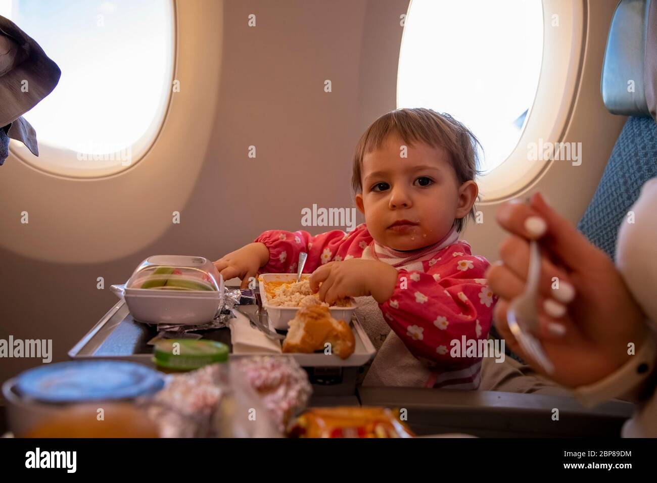 Niedliche Baby Passagier isst in Flugzeug spezielle Mahlzeit. Kleinkind jungen Reisenden Stockfoto