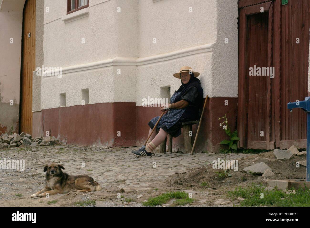 Sibiu County, Transylvania, Rumänien. Ältere Frau auf einer Bank vor ihrem Haus. Stockfoto