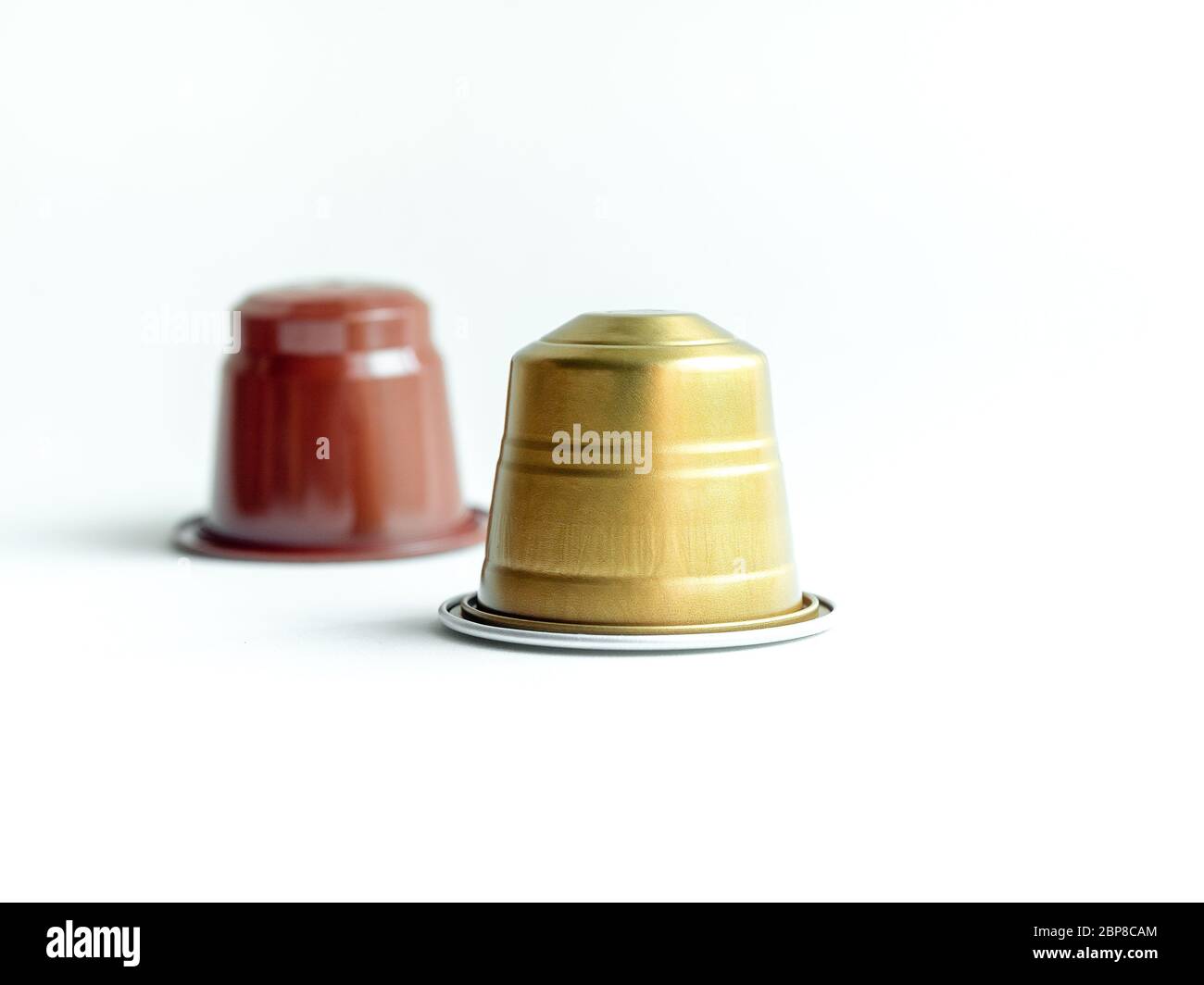 Gold und braun Espresso Kaffeekapseln auf weißem Hintergrund. Stockfoto