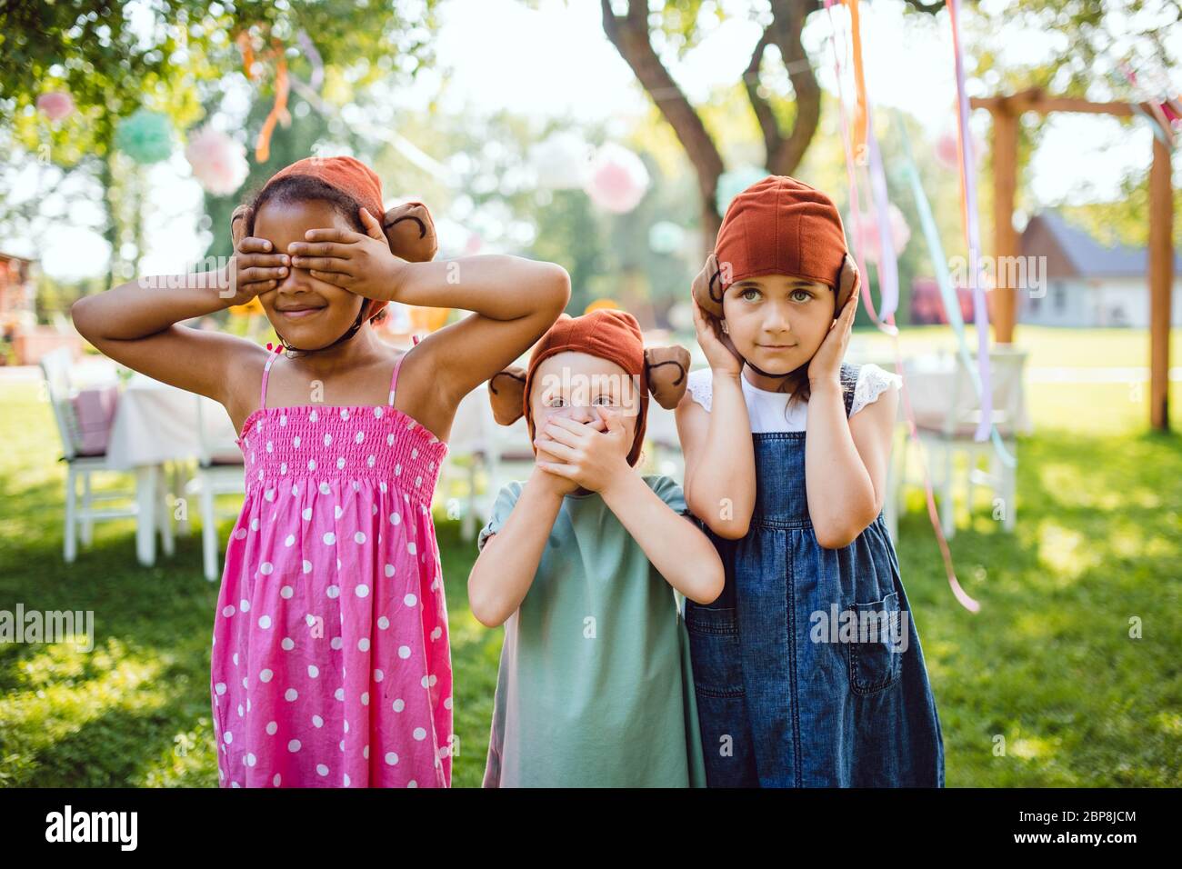 Kleine Kinder mit Masken im Freien auf Gartenparty im Sommer, spielen. Stockfoto
