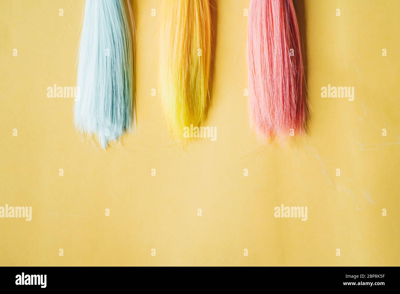 Mehrfarbige, gerade lange Haare, Perücken für handgefertigte Puppen auf  gelbem Hintergrund. Handarbeit, Hobby, Freizeitkonzept. Draufsicht. Farbige  Haarsträhnen Stockfotografie - Alamy