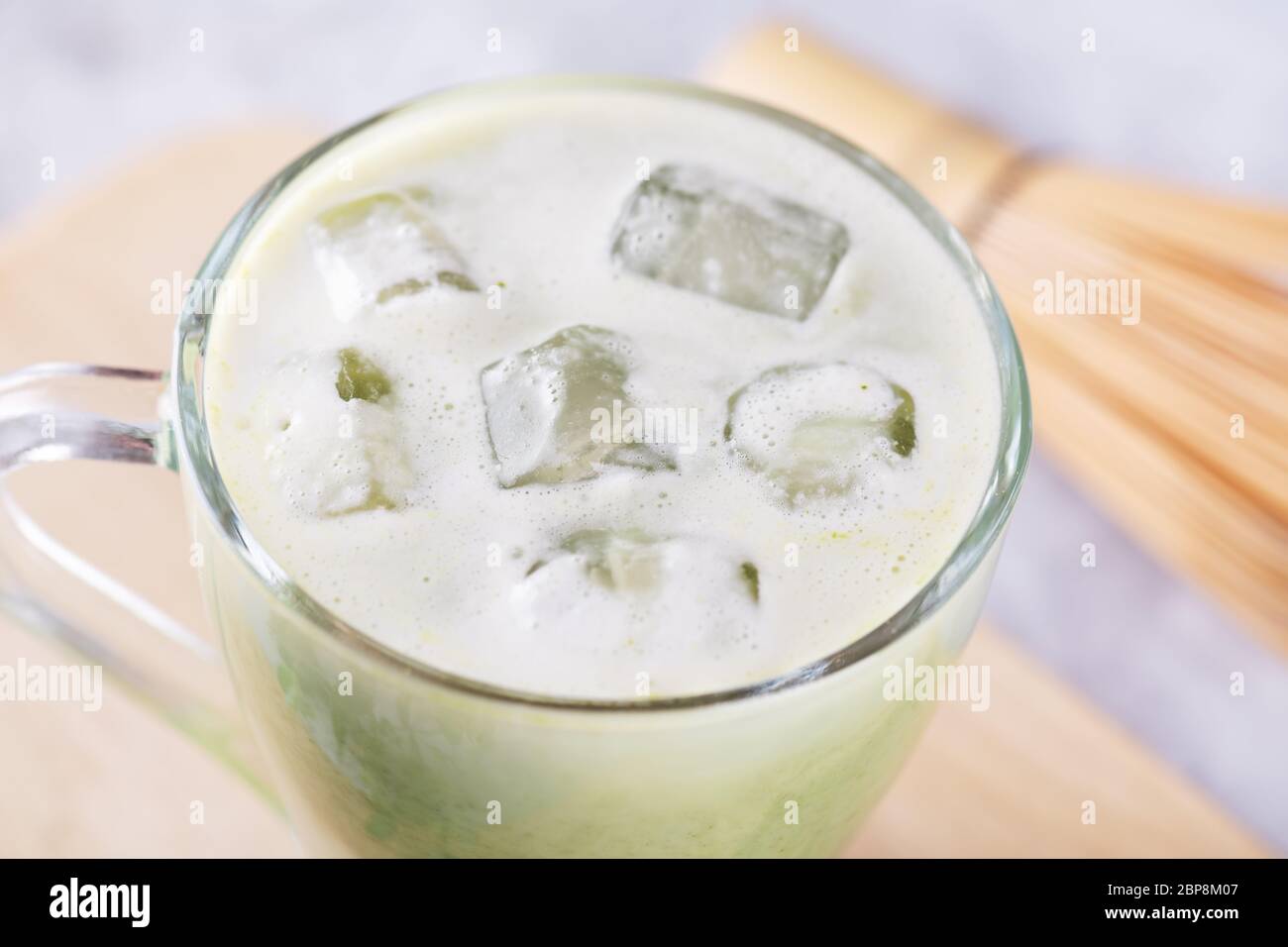 Nahaufnahme eines Eisstückes im Glas mit frischem Matcha Latte, grünem Tee mit Milch Stockfoto