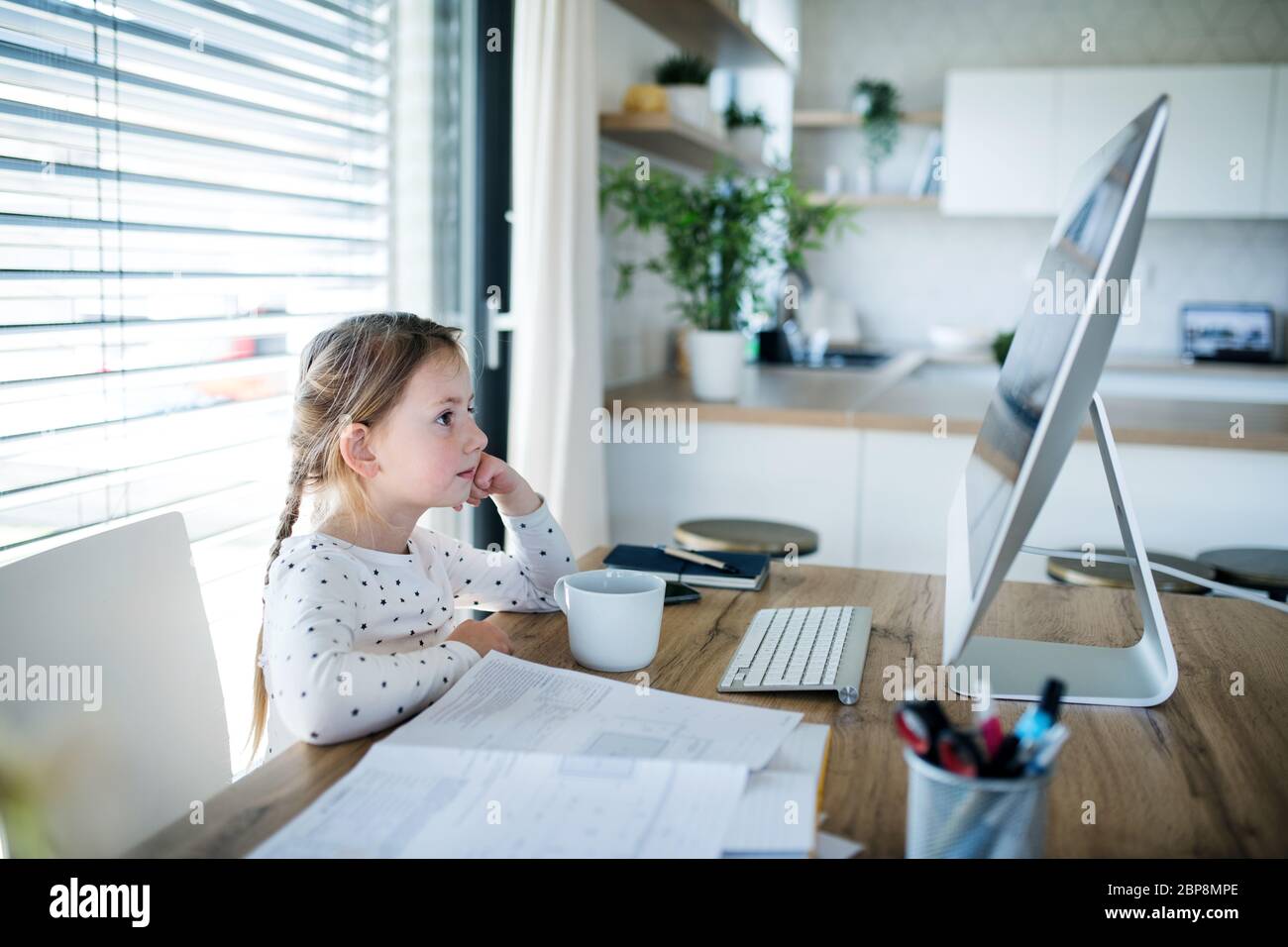 Kleines Mädchen, das zuhause Geschichten am Computer beobachtet, Corona-Virus und Quarantäne-Konzept. Stockfoto