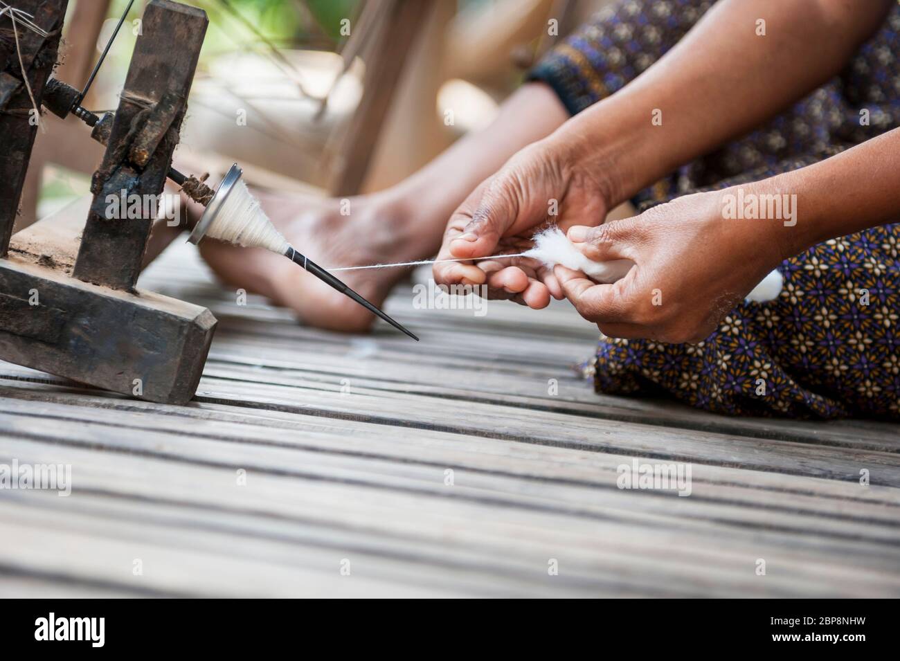 Nahaufnahme der Hände einer Frau, die Seide auf einem traditionellen Spinnrad spinnen. Silk Island, Phnom Penh, Kambodscha, Südostasien Stockfoto