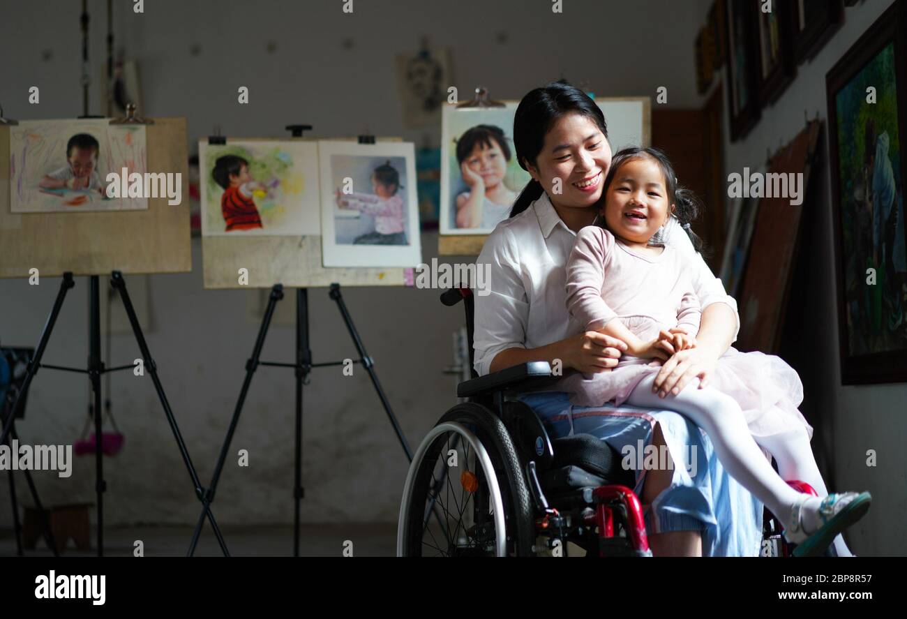 (200518) -- PEKING, 18. Mai 2020 (Xinhua) -- Zhang Haijing und ihre Tochter posieren für ein Foto in ihrem Malraum in der Stadt Dagang im Landkreis Duchang, Ostchinesische Provinz Jiangxi, 7. Mai 2020. Zhang Haijing, 30, wurde nach einem Unfall im Jahr 2008 im Rollstuhl gefesselt. Mit Hilfe der lokalen Behörden gründete Zhang vor einigen Jahren ein Kunststudio in Dagang, in dem er die Kunst der lokalen Kinder unterrichtete und Kunstwerke für den Online-Verkauf schuf. Derzeit hat die Familie die Armut abgeschüttelt, da sich ihre finanzielle Situation stark verbessert hat. Mehr als 93 Millionen Menschen in den ländlichen Gebieten Chinas haben seit 20 die Armut erschüttert Stockfoto