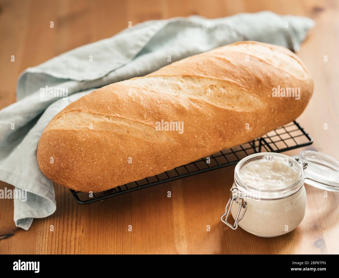 Britisches Weißblüher oder europäischer Sauerteig Baton Laib Brot auf Holzhintergrund. Frisches Brot und Glas mit Sauerteig Starter. Kopierbereich Stockfoto