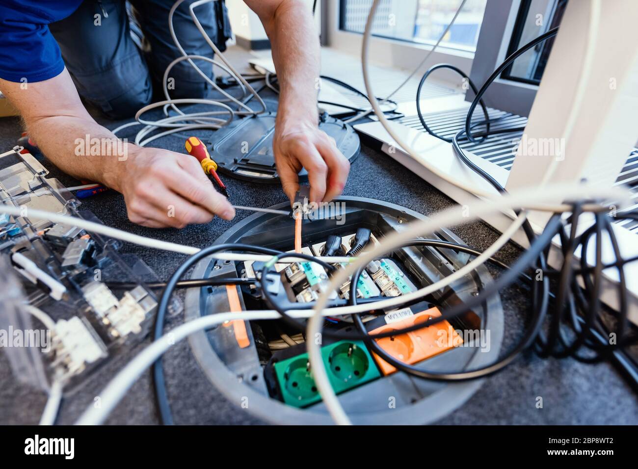 Kabel, Steckdosen, IT-Kommunikation und die Hände eines Elektrikers. Stockfoto