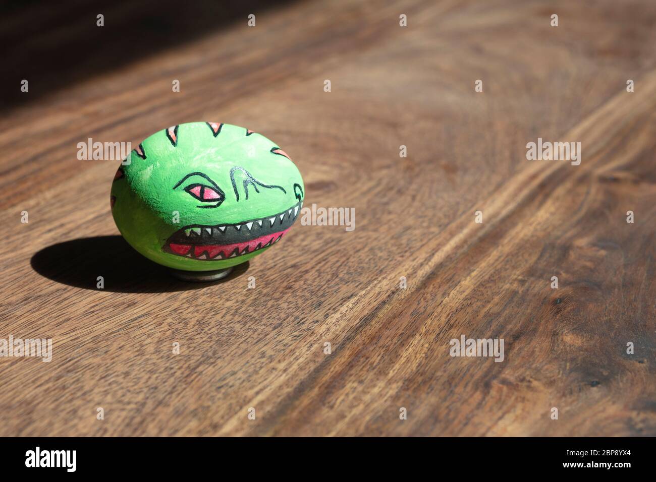 Bunt gemaltes Dino Osterei im Holzhintergrund. Stockfoto