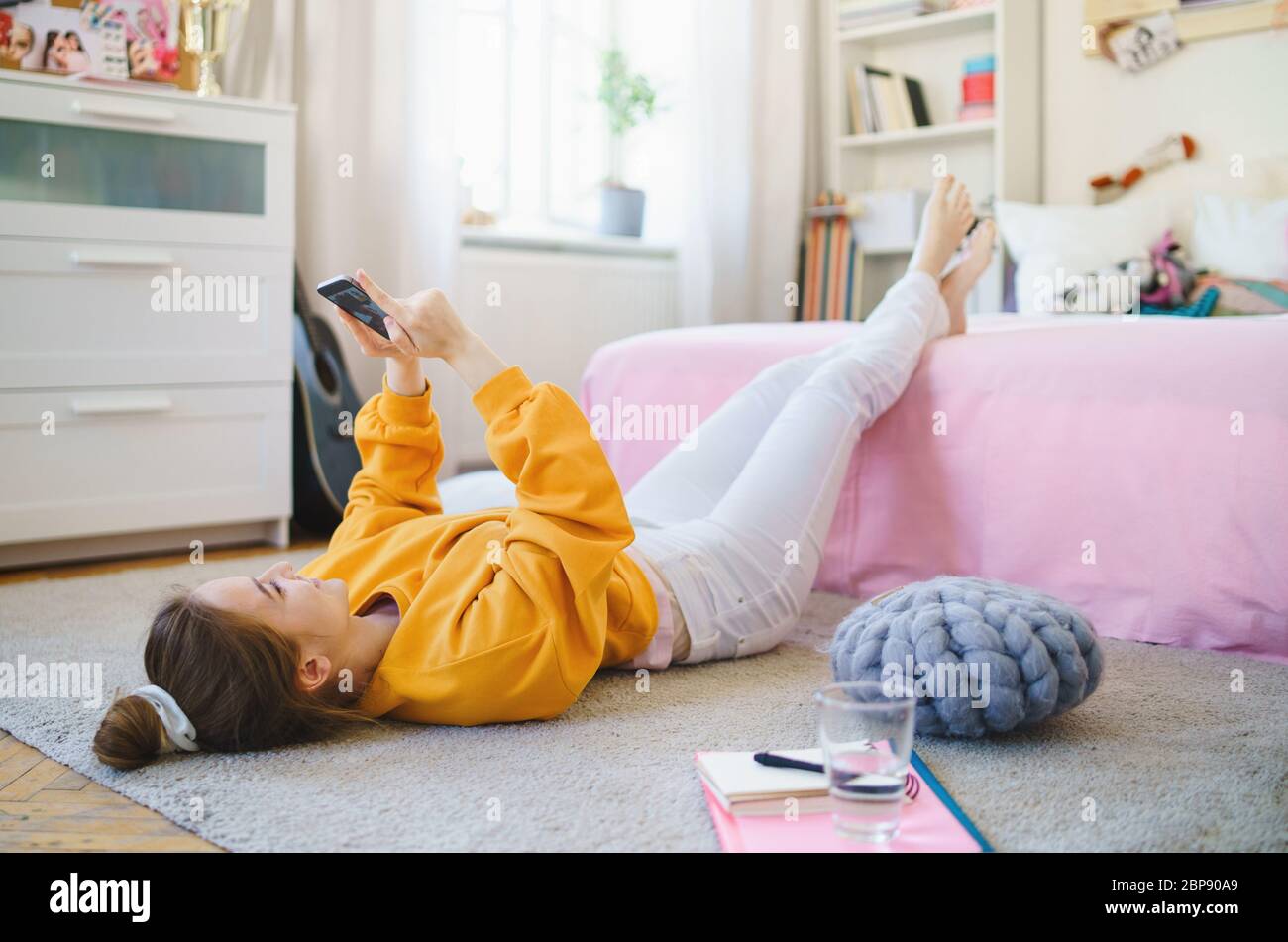Junges Mädchen mit Smartphone auf dem Boden zu Hause, Videoanruf. Stockfoto