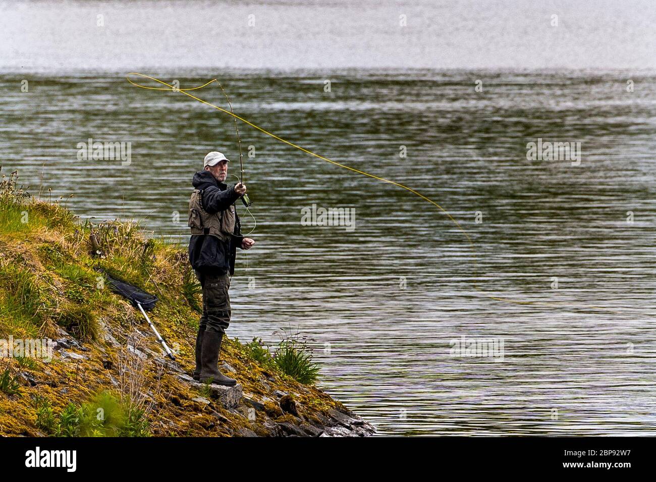Ein Angler Fliegenfischen am Ufer des Ballysallagh Lower Reservoir nur Bangor, Nordirland als Angler haben sich erlaubt, Angeln gehen, wie die Lockdown erleichtert. Stockfoto