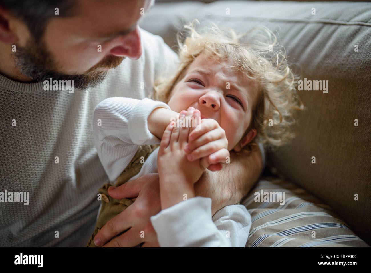 Vater mit kleinen kranken weinenden Kleinkind Tochter zuhause. Stockfoto