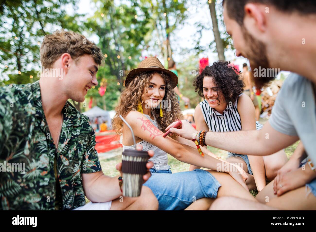 Gruppe junger Freunde, die auf dem Boden beim Sommerfest sitzen. Stockfoto