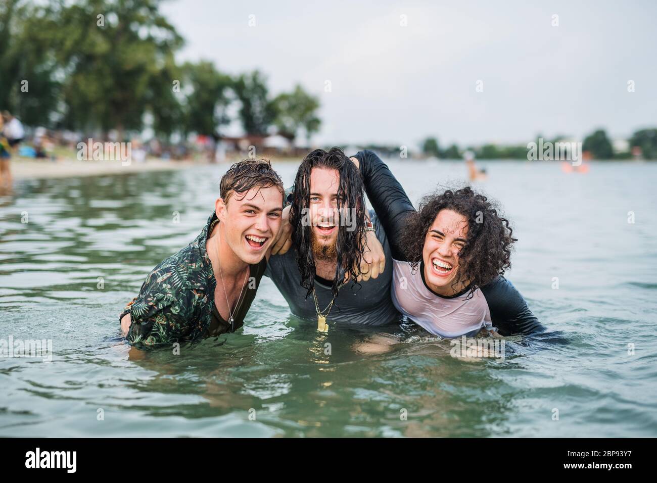 Gruppe von nassen jungen Freunden beim Sommerfest, im See stehend. Stockfoto