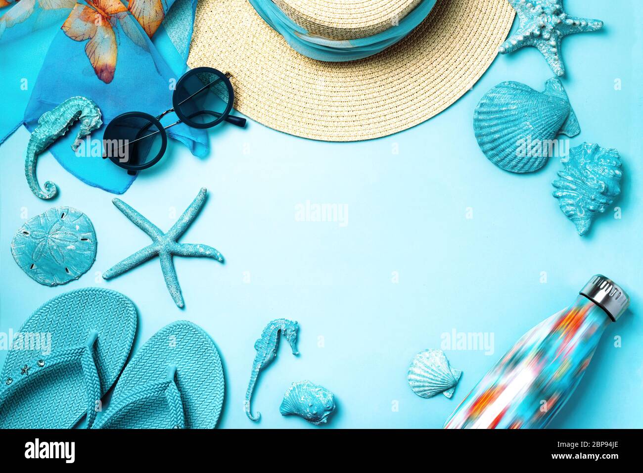 Sommer Mode auf blauem und korallenfarbenem Hintergrund. Blaue Flip Flops, Muscheln, Sonnenbrille, Flasche und Strohhut. Flaches Layout, Draufsicht mit Kopierfläche. Stockfoto