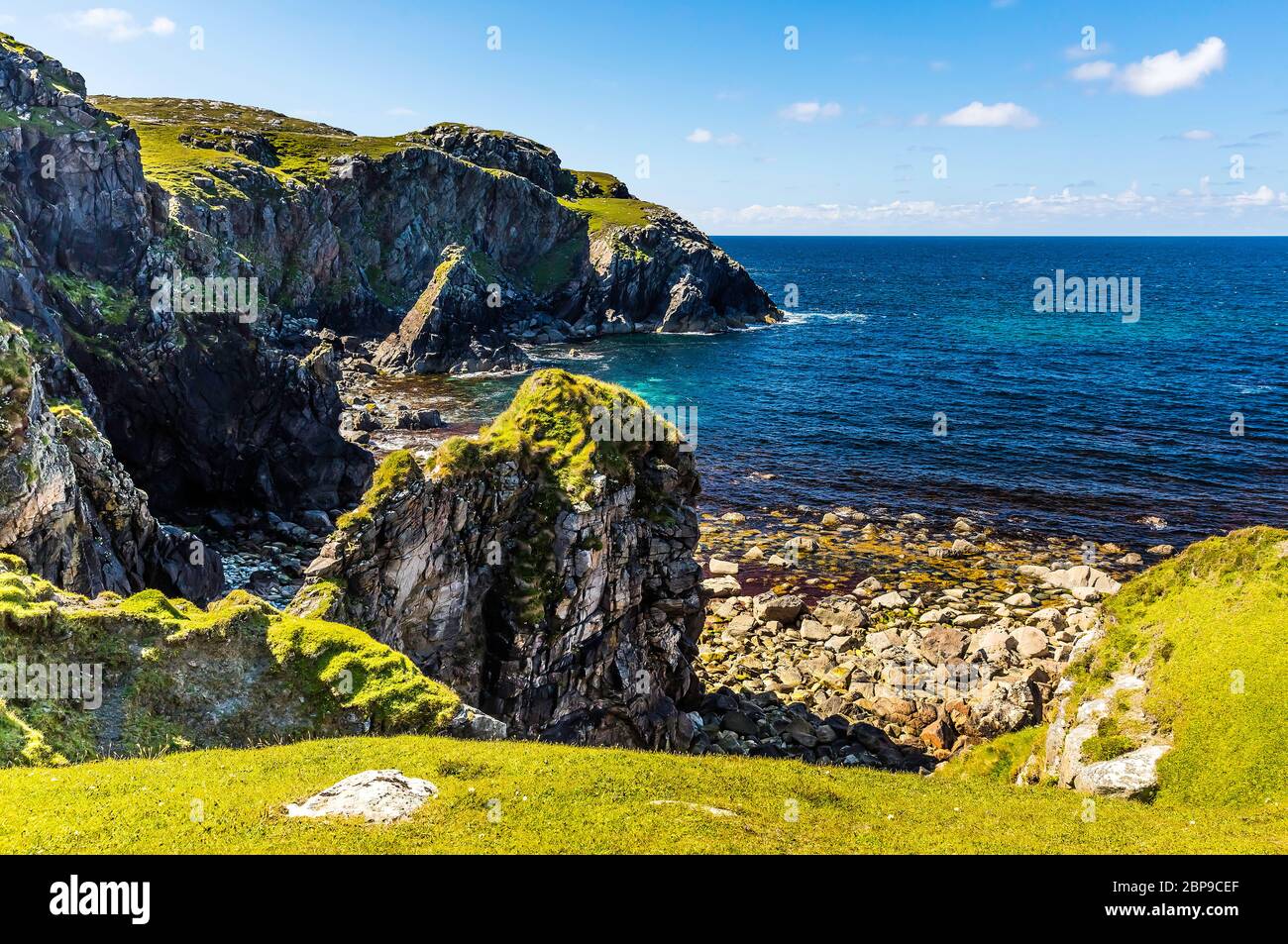 Auf dem Weg zum Meer finden Sie an einem sonnigen Tag grüne Felsen und Klippen an Schottlands Küste. Stockfoto