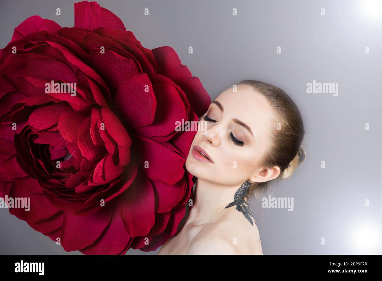 Schönes Mädchen mit gesunder Haut entspannt nach einer Spa-Behandlung mit einer roten Blume Stockfoto