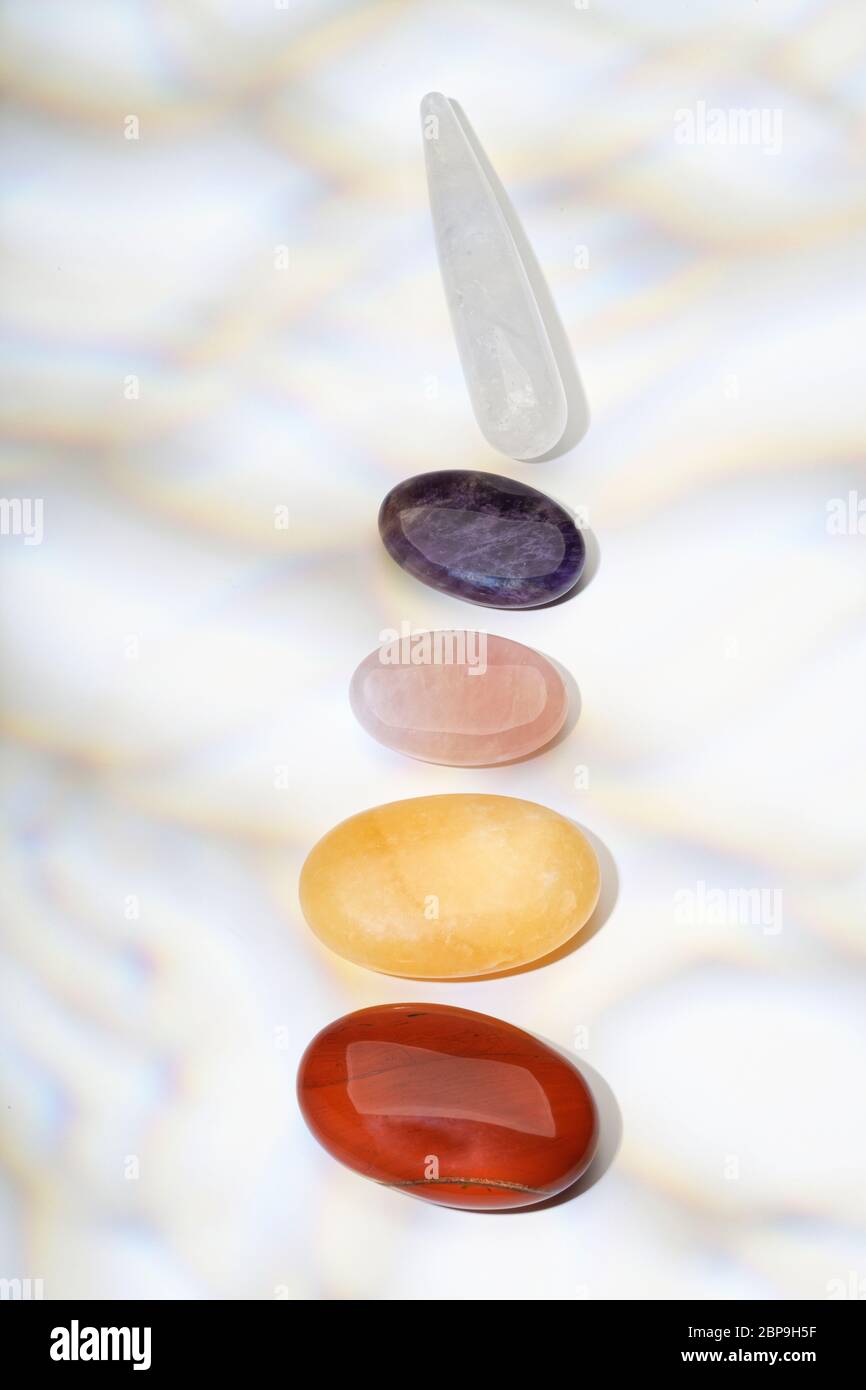 Halbedelsteine in einer Reihe. Granat, Karneol, Rosenquarz, Lapis Lazuli, Amethyst und Quarz. Chakren. Stockfoto