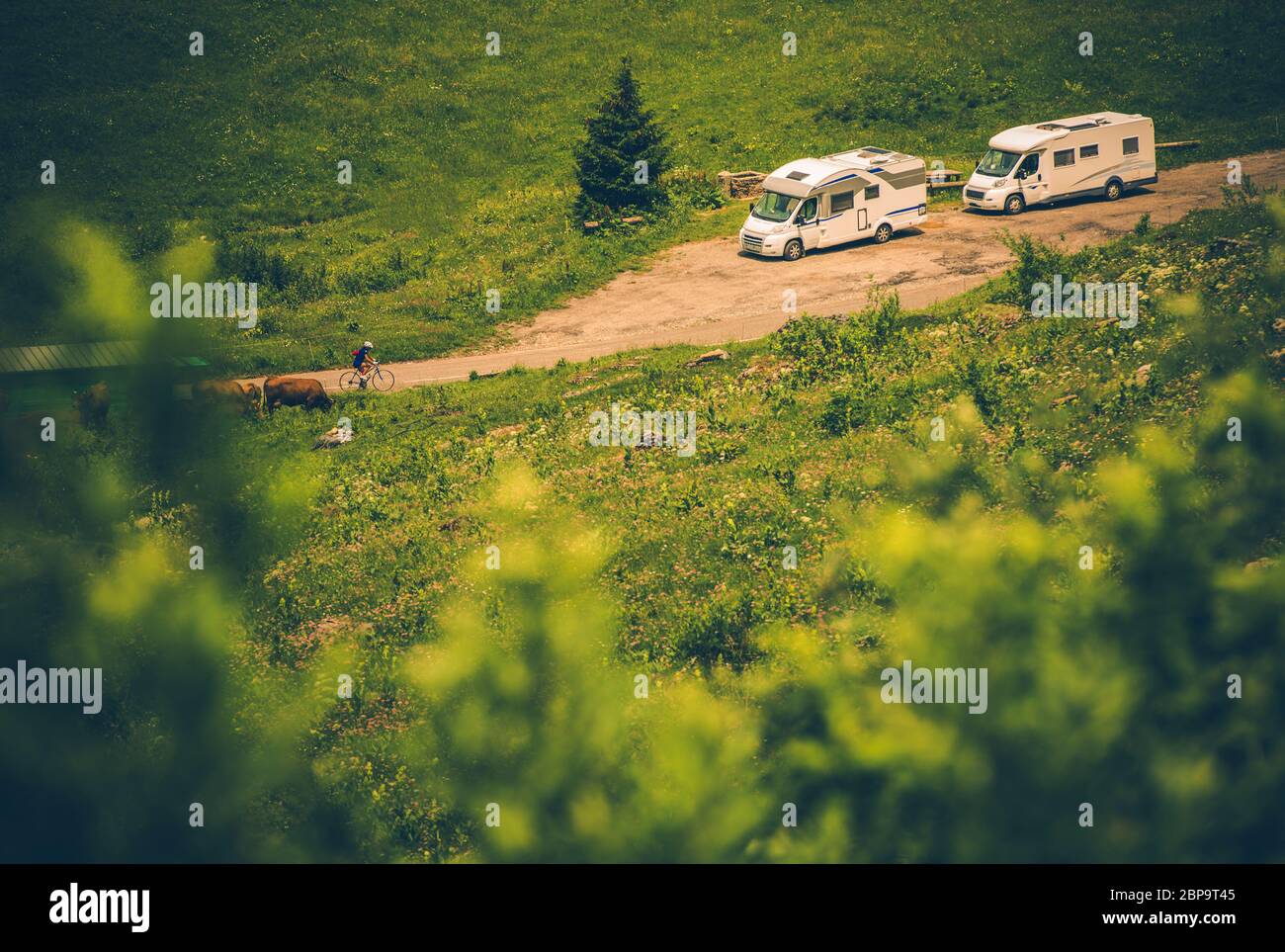 Zwei Weiße Mittelgroße Freizeitfahrzeuge, Die Auf Der Seite Der Rural Dirt Road Geparkt Sind. Stockfoto