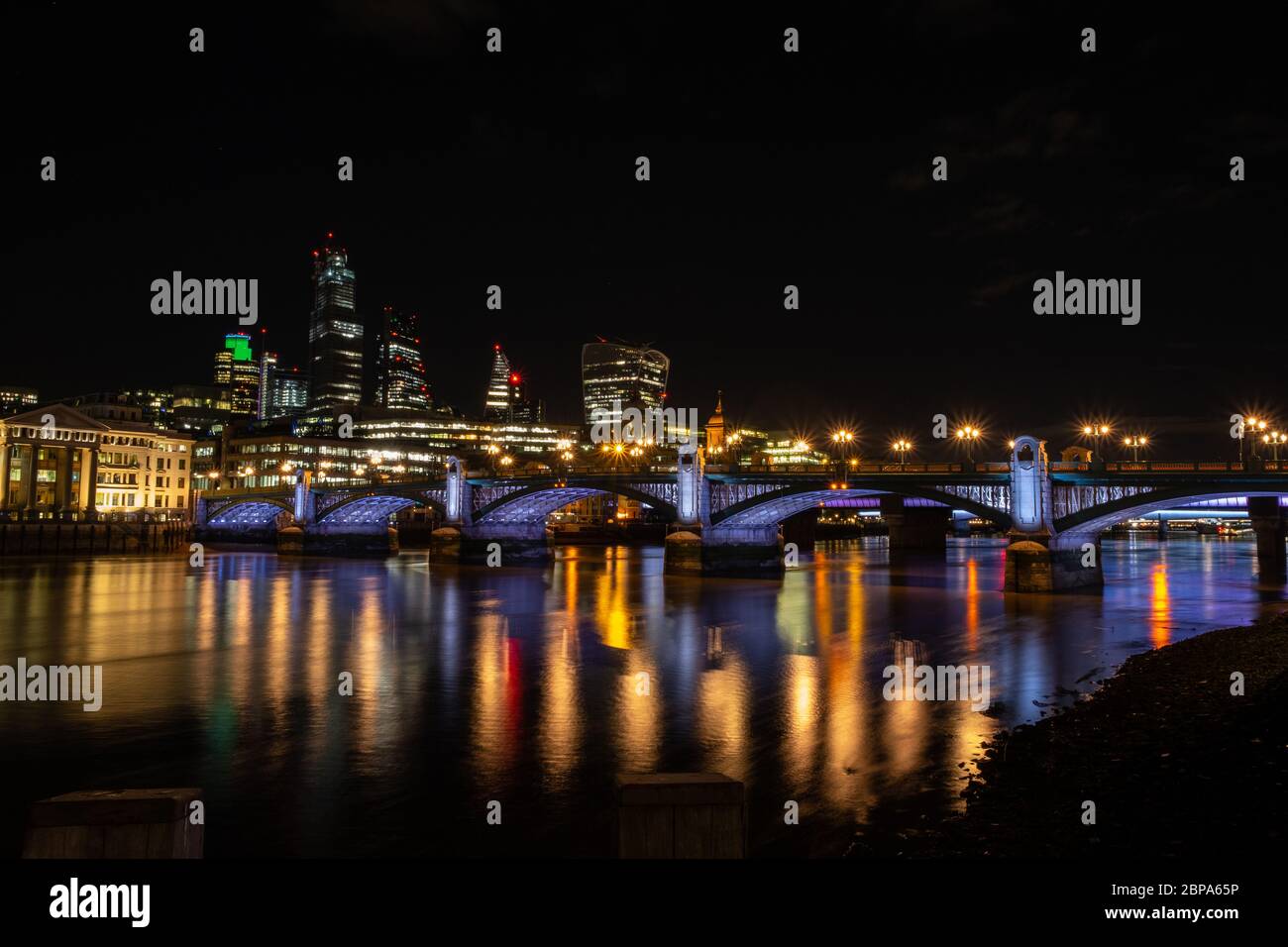 Southwark Bridge bei Nacht vom Südufer mit City of London im Hintergrund. Beleuchtetes Flussprojekt Stockfoto