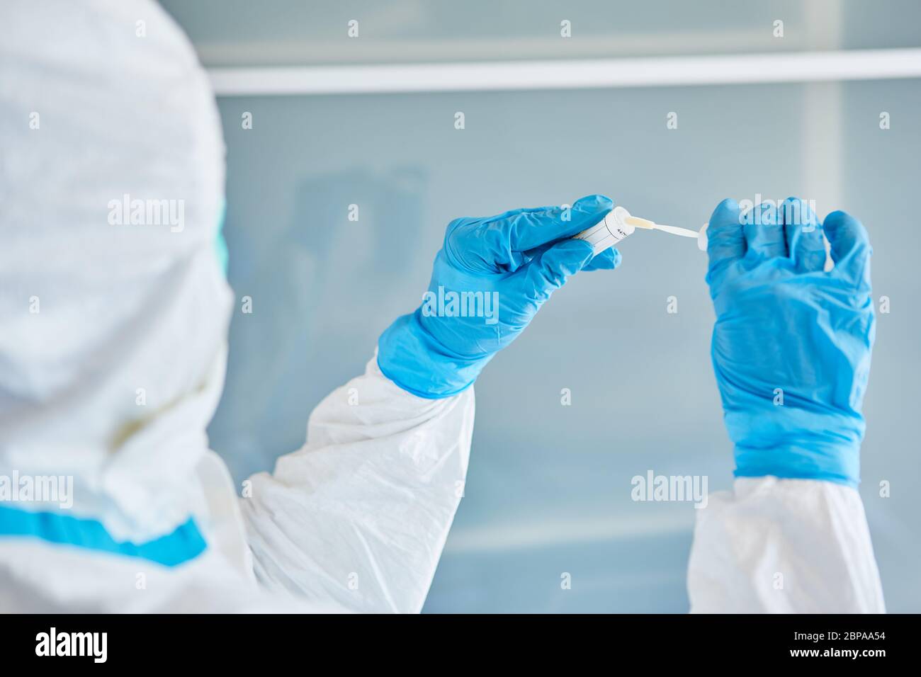 Medic in Schutzkleidung hält Rachenabstrich an Speichelprobe für Coronavirus-Test Stockfoto