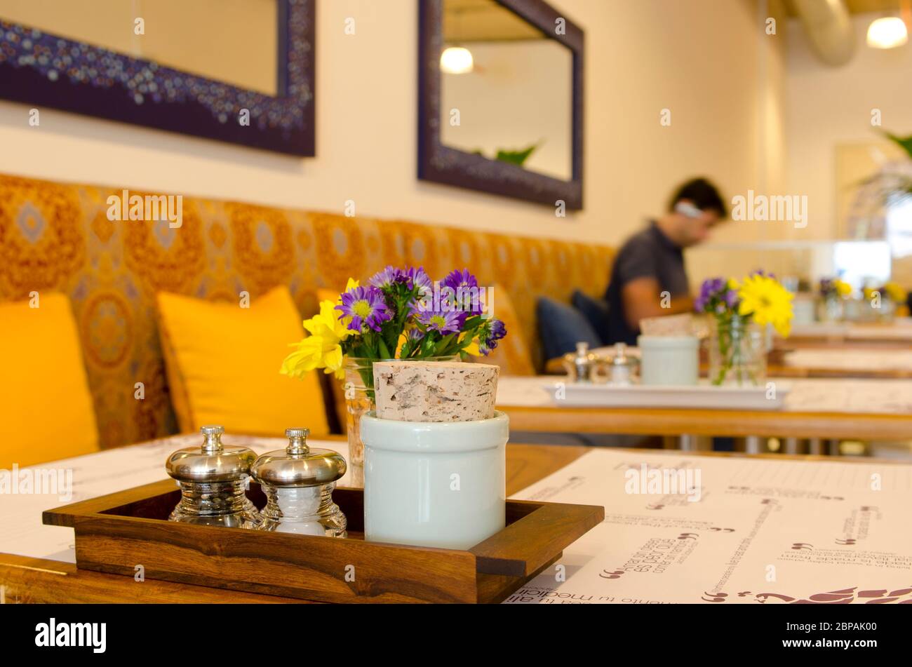 Holztisch im Café mit Blumenarrangement und Salz & Pfeffer und Zucker Stockfoto