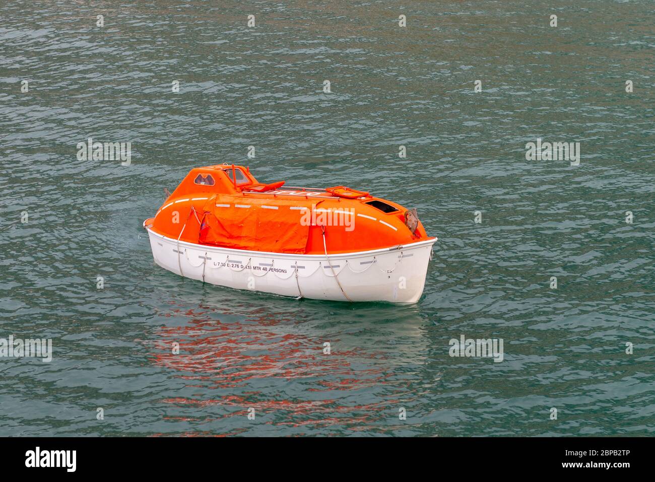 Manövrieren orange Rettungsboot im Wasser in arktischen Gewässern, Spitzbergen. Schiffsangebohrung abbrechen. Rettungsboot-Training. Mann über Bord Bohrer. Stockfoto