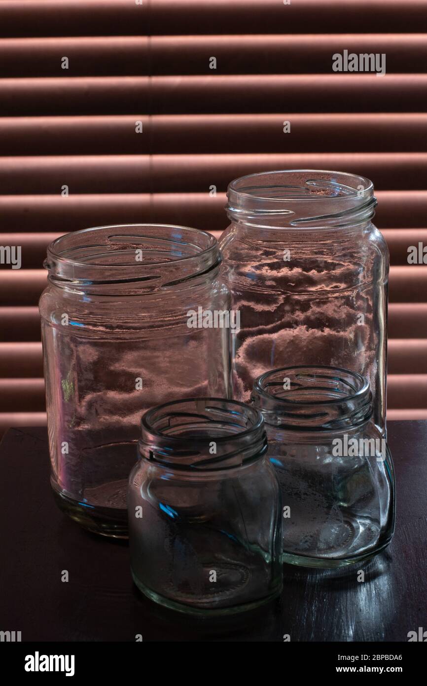 Vier leere, gebrauchte und leicht verschmutzte Glasgefäße. Stockfoto